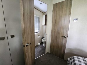 A compact bathroom with a toilet, a small window, and a shower area. - D&ashortbreaks-stmargaretsbay-parking (Dover)