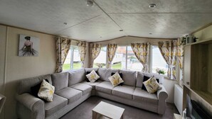 A living room with a grey sectional sofa, a coffee table, and a flat-screen TV. - D&ashortbreaks-stmargaretsbay-parking (Dover)