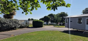 A residential area with a paved road, a speed limit sign, and mobile homes. - D&ashortbreaks-stmargaretsbay-parking (Dover)