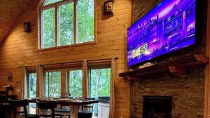 Un interior acogedor con chimenea, una mesa redonda de madera y un televisor montado en la pared.