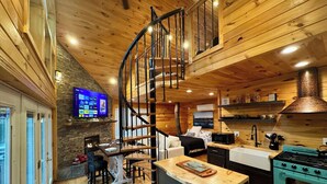 A modern kitchen with a central island, a built-in stove, and a spiral staircase. - Treehouse Duo Lakefront  2 Private Hot Tubs (Belgrade)