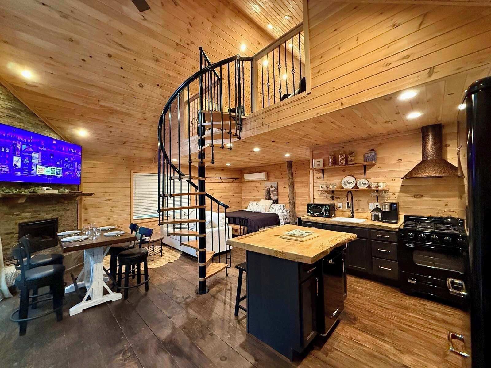 A cabin interior with a spiral staircase, a kitchen with a stove, and a dining area with a table and chairs.