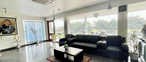 A spacious living area with a black leather sofa, a coffee table, and potted plants.