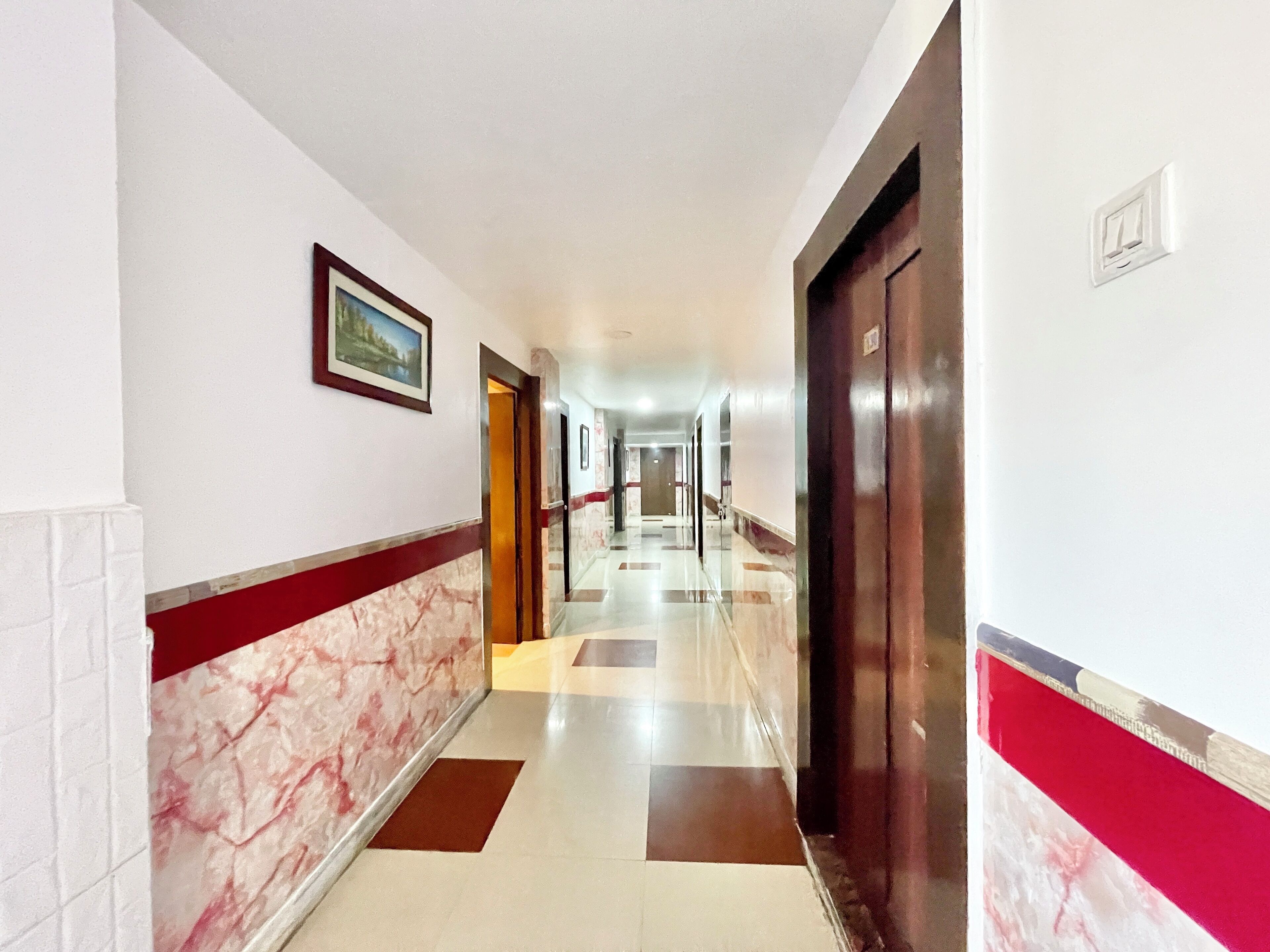 Un pasillo de hotel con pared de mármol, un cuadro enmarcado y una puerta.