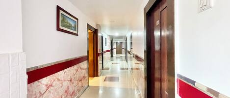 A hotel corridor with a marble wall, a framed picture, and a door.