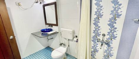 A bathroom with a toilet, sink, shower curtain, and a bucket.