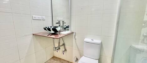 Un baño con un inodoro blanco, un lavabo con una pileta blanco y negro, y un espejo sobre el lavabo.