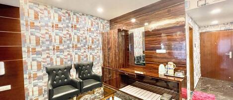 Un salon moderne avec un mur à motifs, une table basse en verre et un coin salon composé de deux canapés noirs.