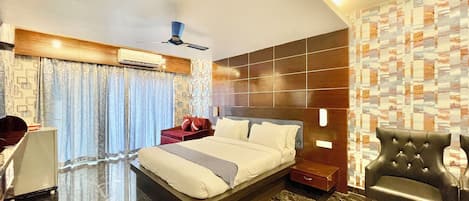 A modern hotel room with a large bed, a desk, a chair, and a ceiling fan.