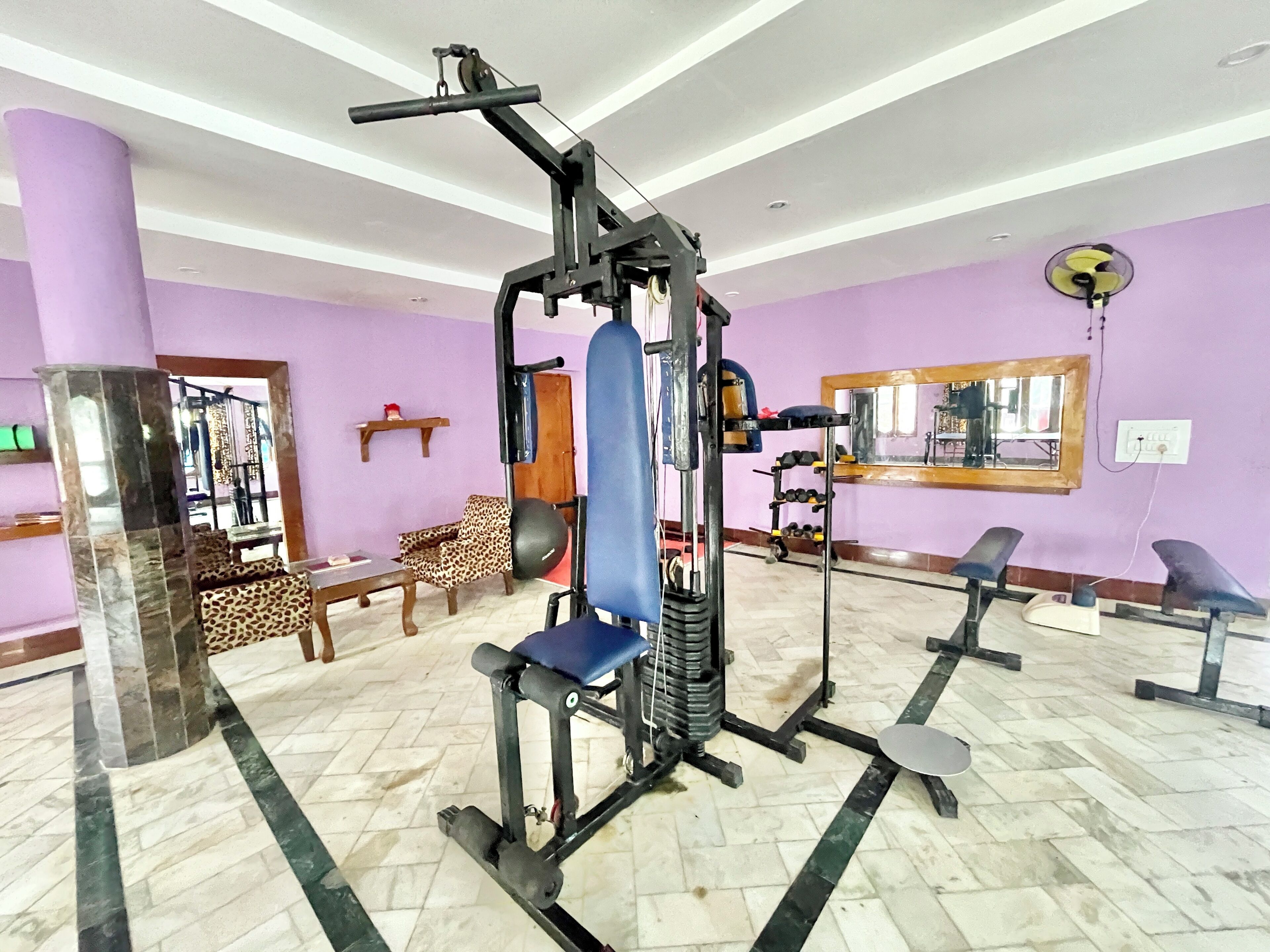 Une salle de sport équipée de matériel d’exercice, d’un miroir et d’un espace détente avec un fauteuil à motifs léopard.