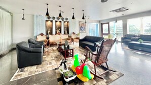 A spacious living room with a large sofa set, a coffee table, and a decorative scooter. - Hotel V-i sea view - Puri  (Puri)