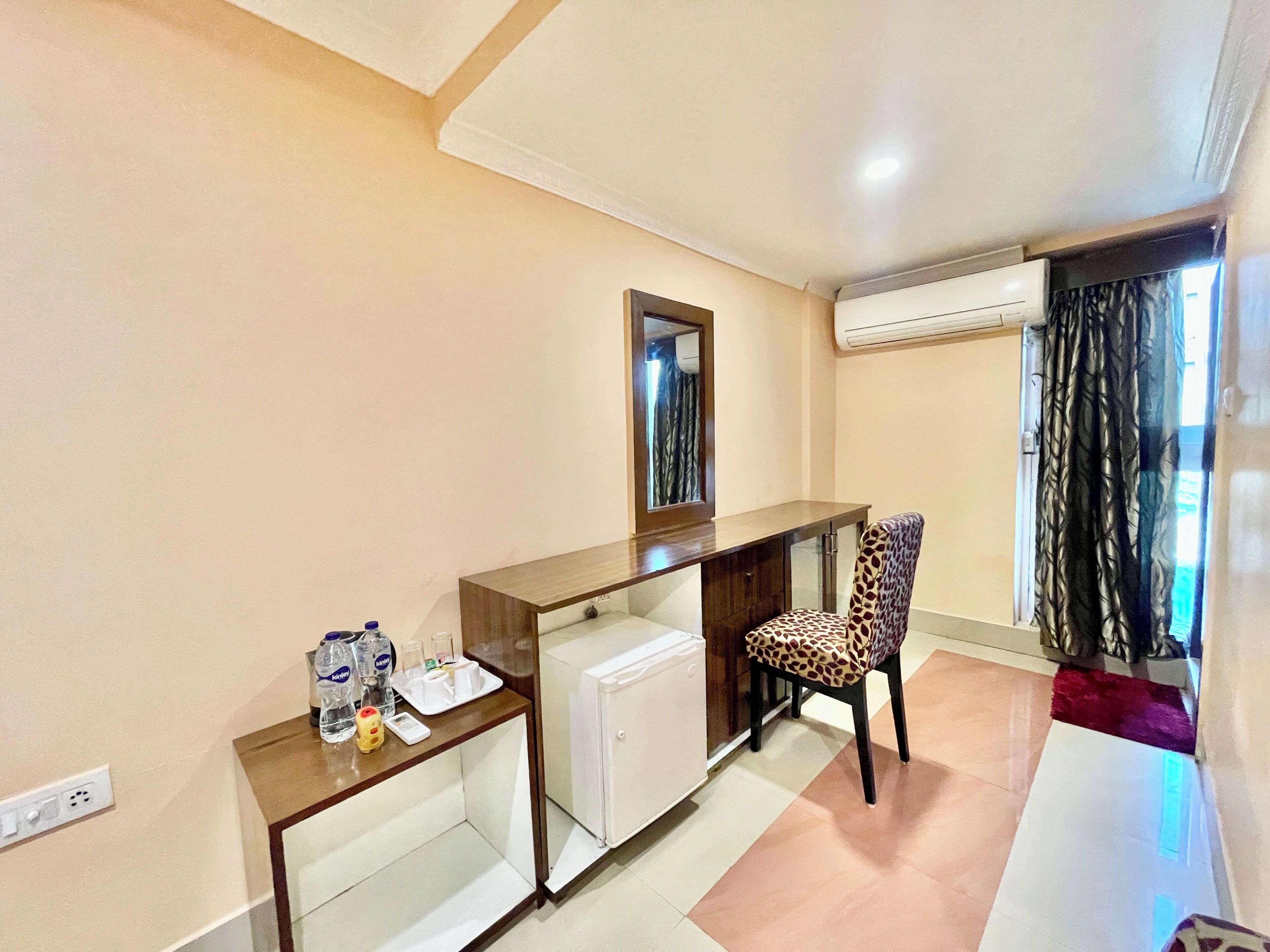 A small, clean room with a desk, chair, and a window with curtains.