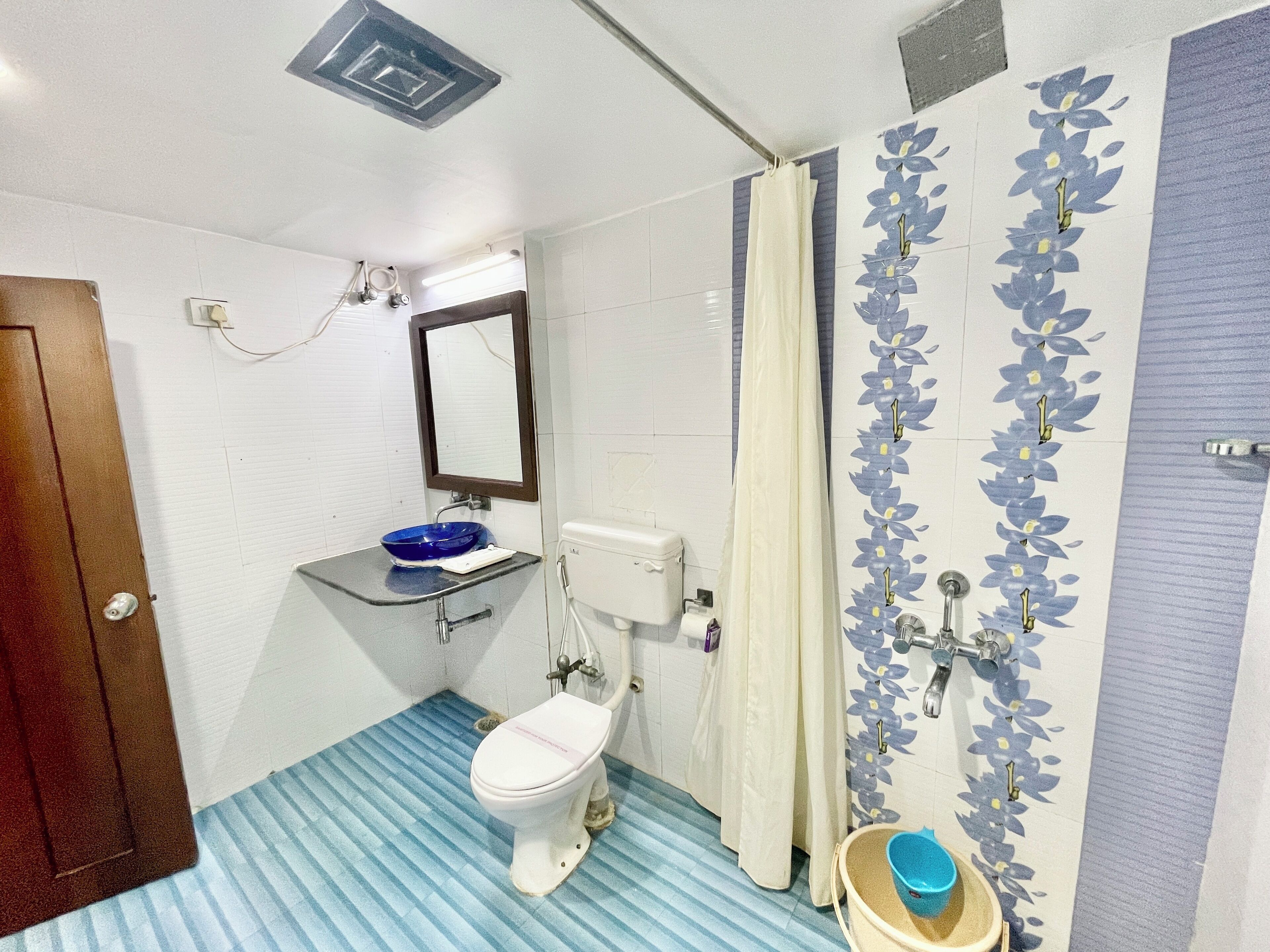 Un baño con inodoro, lavamanos, ducha y piso azul a rayas.