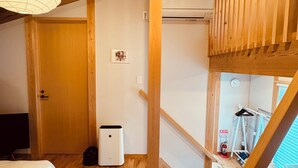 A wooden interior with a bed, a waste bin, and a staircase. - CrossFit Otoyo Strength TINY HOUSE (Otoyo)