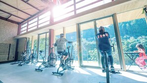 A gym with exercise bikes and a large window overlooking a forested area. - CrossFit Otoyo Strength TINY HOUSE (Otoyo)