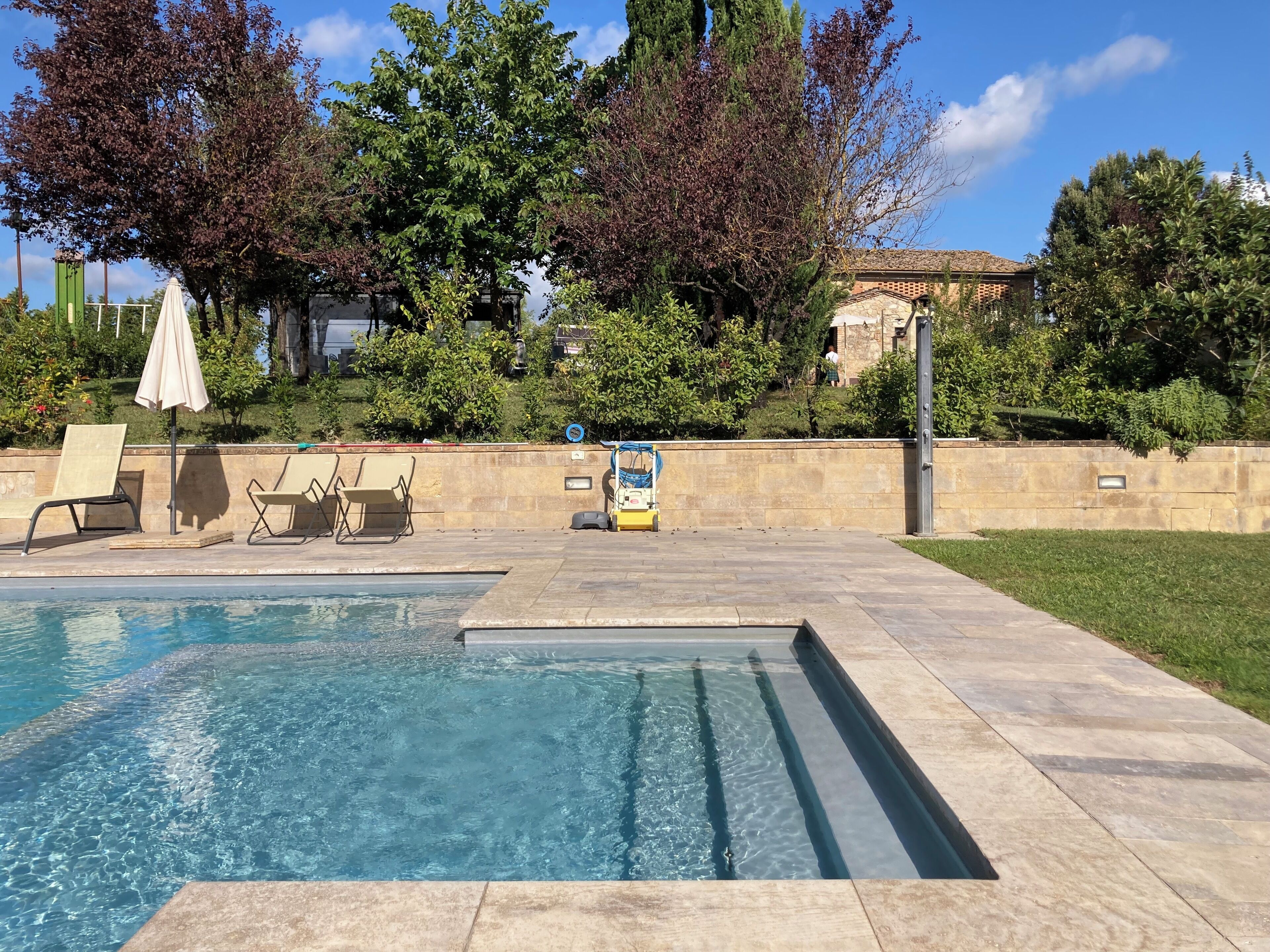 A swimming pool with two lounge chairs and a small umbrella.