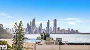 A coastal cityscape with high-rise buildings, a beach, and a clear sky.