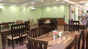 A conference room with a marble table, wooden chairs, and green walls. - Royal Park Celebration By GRB (Patna)