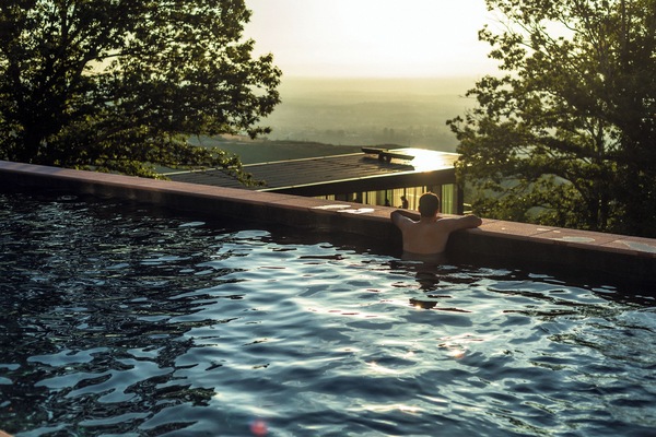 Una piscina al aire libre, sombrillas, sillones reclinables de piscina