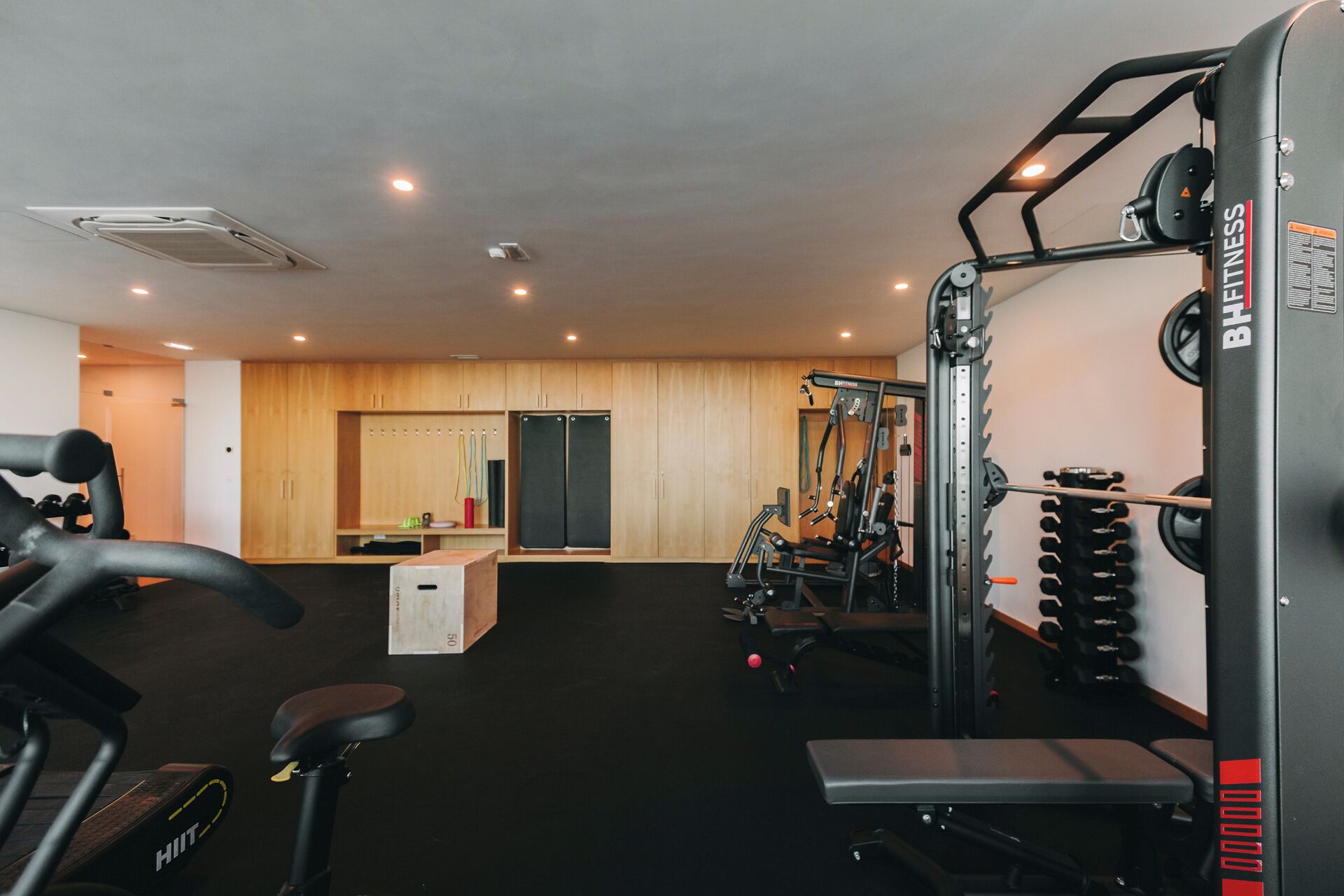 A gym with various exercise equipment, including a bench, a squat rack, and a treadmill.