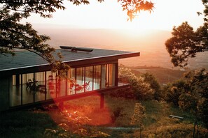A modern house with a glass exterior, a balcony, and a view of the landscape. - Estrela Serenity - Resort (Gouveia)