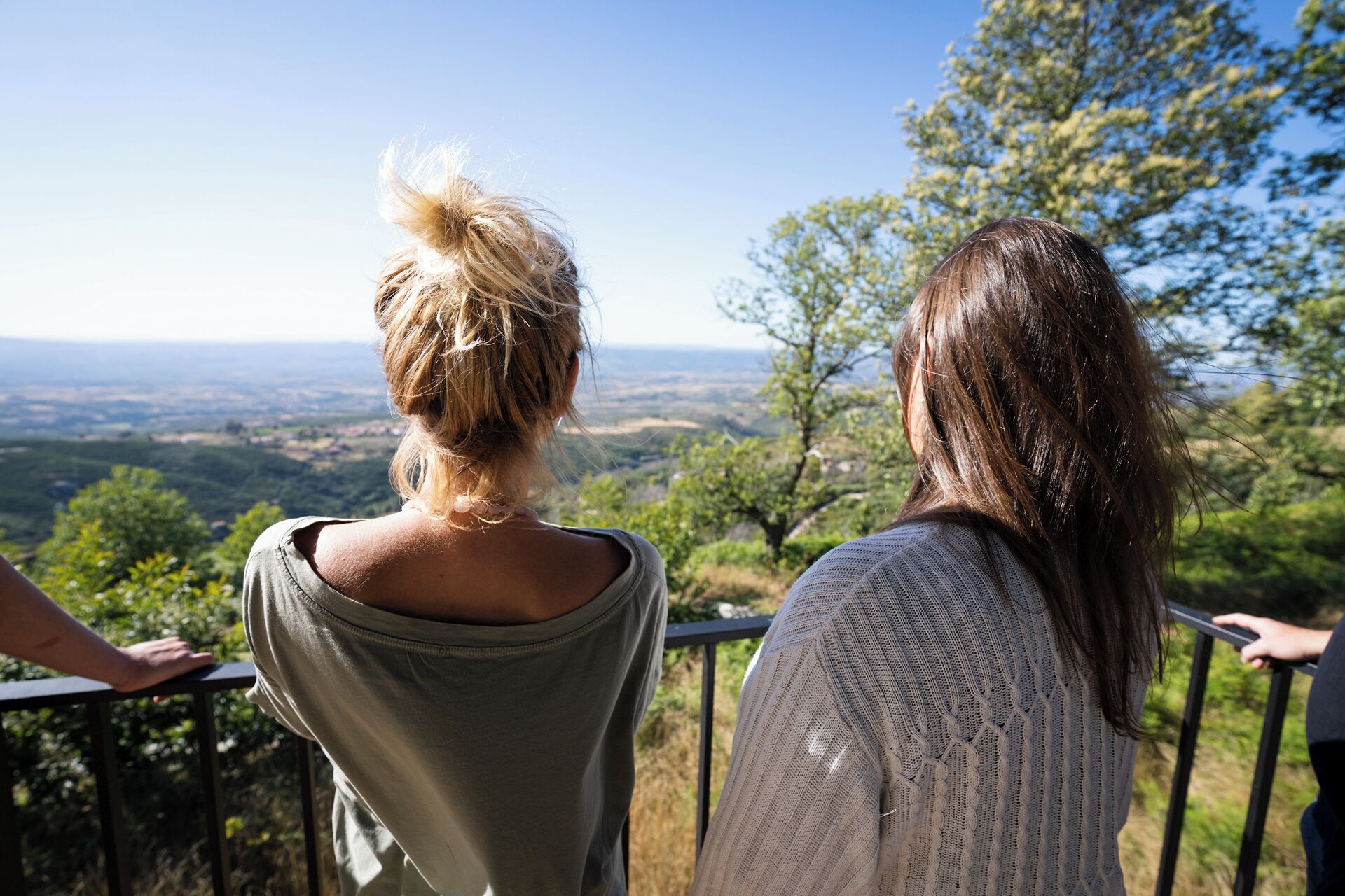 Deux personnes contemplent un paysage magnifique depuis un balcon doté d’une rambarde en métal.