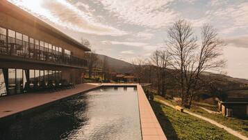 Een buitenzwembad, parasols bij het zwembad en ligstoelen