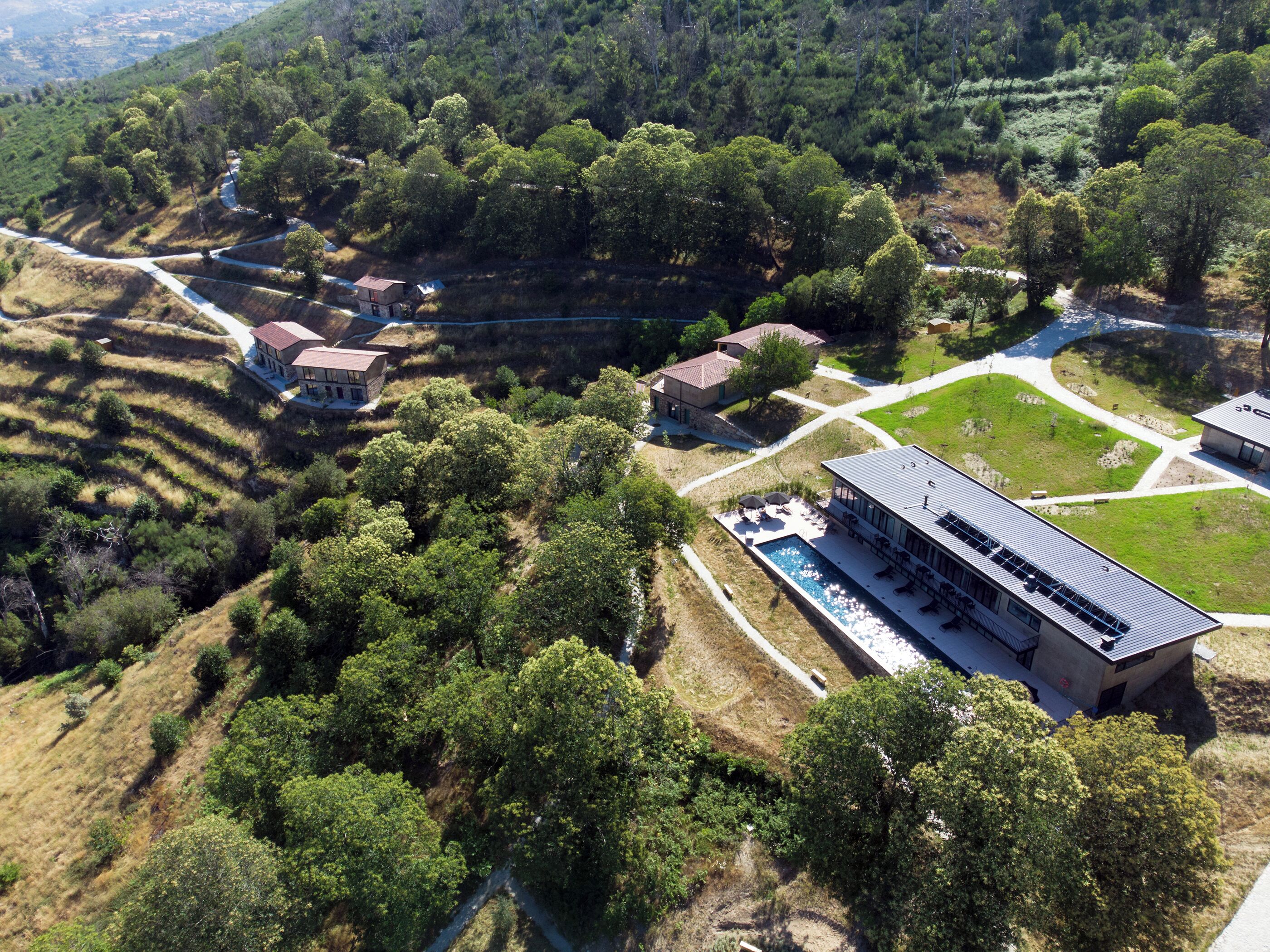 Vista aérea de una zona residencial con varias casas, una piscina y un edificio grande con techo plano.