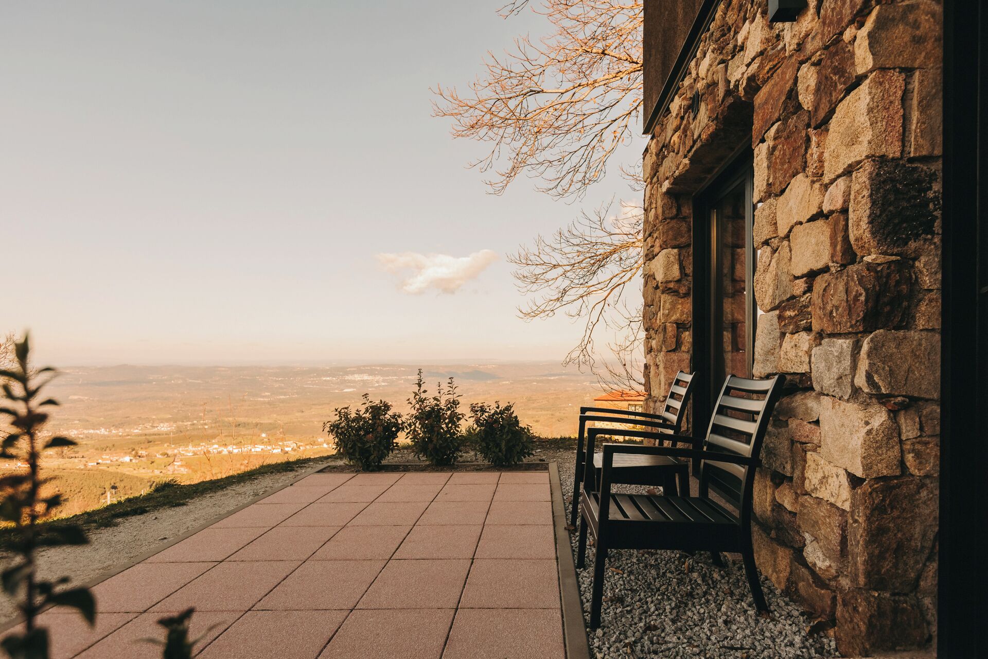 Un edificio de piedra con un banco y vistas a un paisaje lejano.
