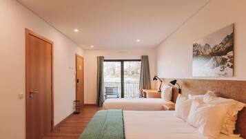Habitación de hotel con dos camas, un escritorio, una silla, una lámpara y un amplio ventanal con cortinas.