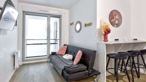 Ein modernes Wohnzimmer mit einer Couch, einem Couchtisch und einem Essbereich mit Barhocker.