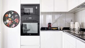 A kitchen with white cabinets, a black microwave, and a coffee maker.