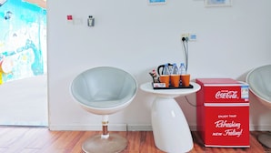 Une pièce moderne avec un mur blanc, une table en verre, une chaise blanche et une boîte rouge de Coca-Cola.