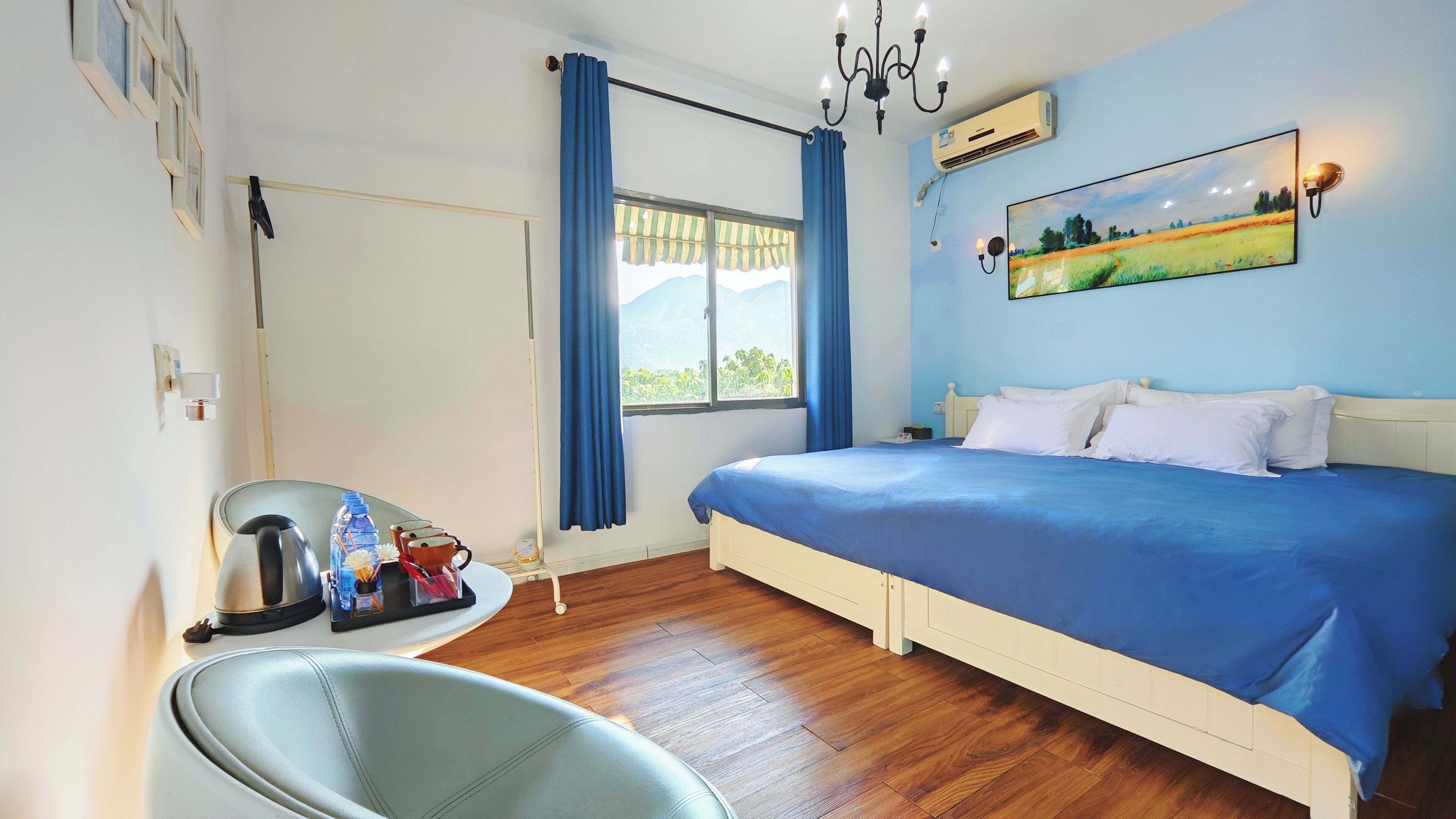 Une chambre à coucher avec un lit, une chaise, une fenêtre avec des rideaux, un tableau au mur et un luminaire au plafond.