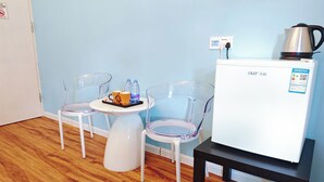 Une petite cuisine équipée d’un réfrigérateur blanc, d’une machine à café et d’une table avec deux chaises.
