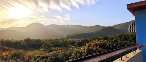 A balcony with a view of mountains and a sunset.