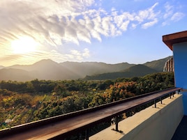 A balcony with a view of mountains and a sunset.