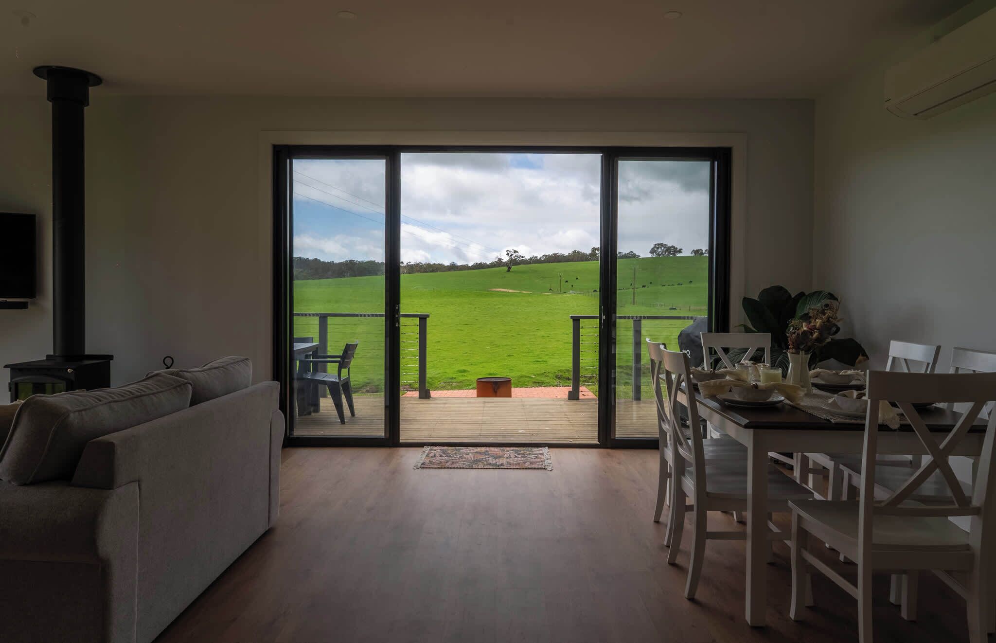 A living room with a large sliding glass door leading to a balcony with a view of a green field.
