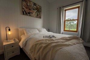 A bedroom with a bed, a nightstand with a lamp, a cup, and a book. - The Old Farm Cottage, Mount Torrens (Mount Torrens)
