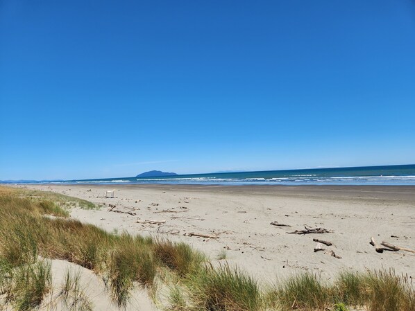 Enjoy a serene beach experience with gentle waves and a stunning mountain backdrop.