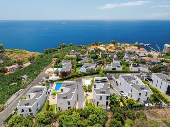 A coastal residential area with modern houses, a clear view of the ocean, and a small boat in the distance.
