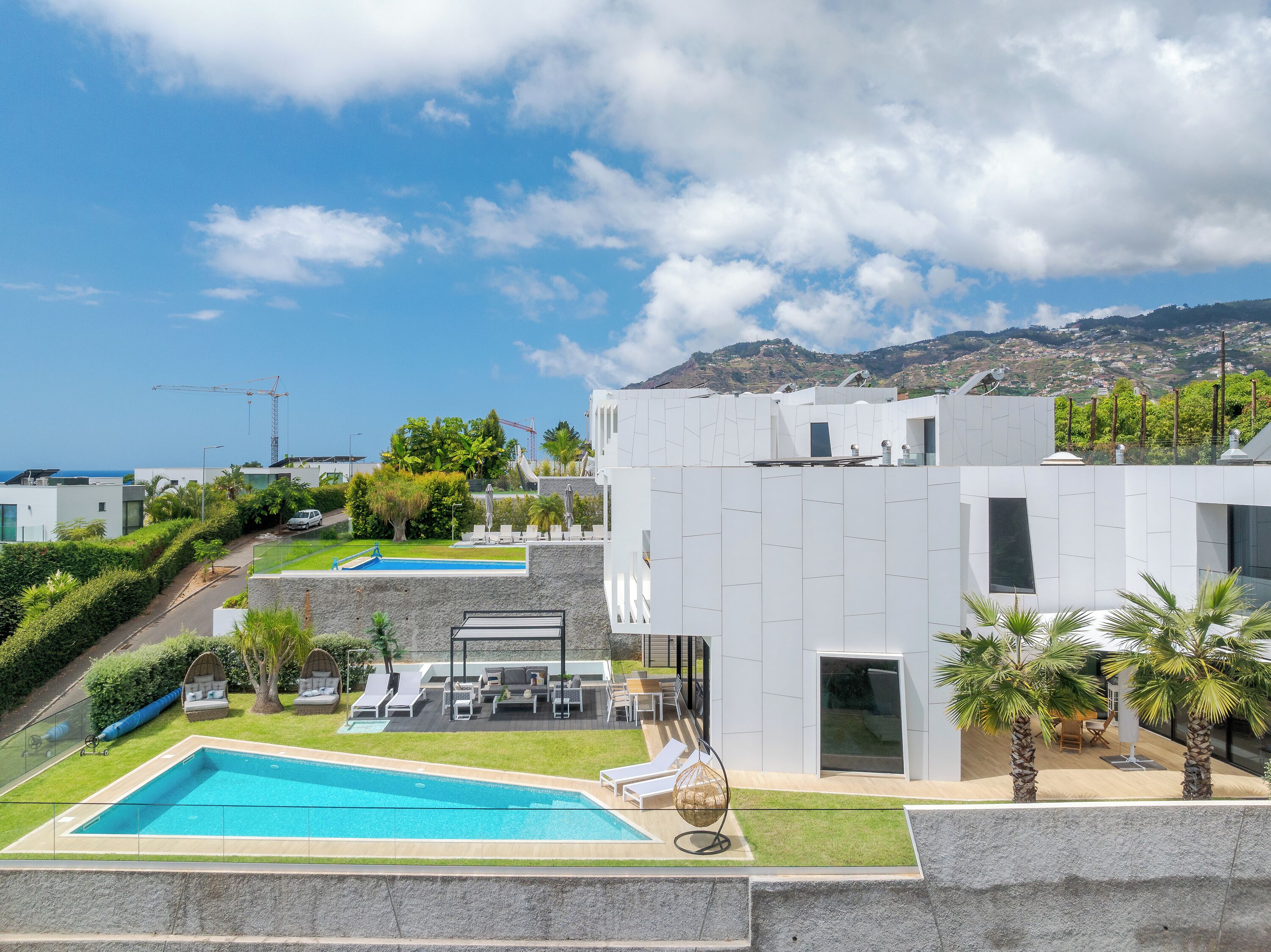 A modern building with a swimming pool, outdoor seating, and a view of the mountains.