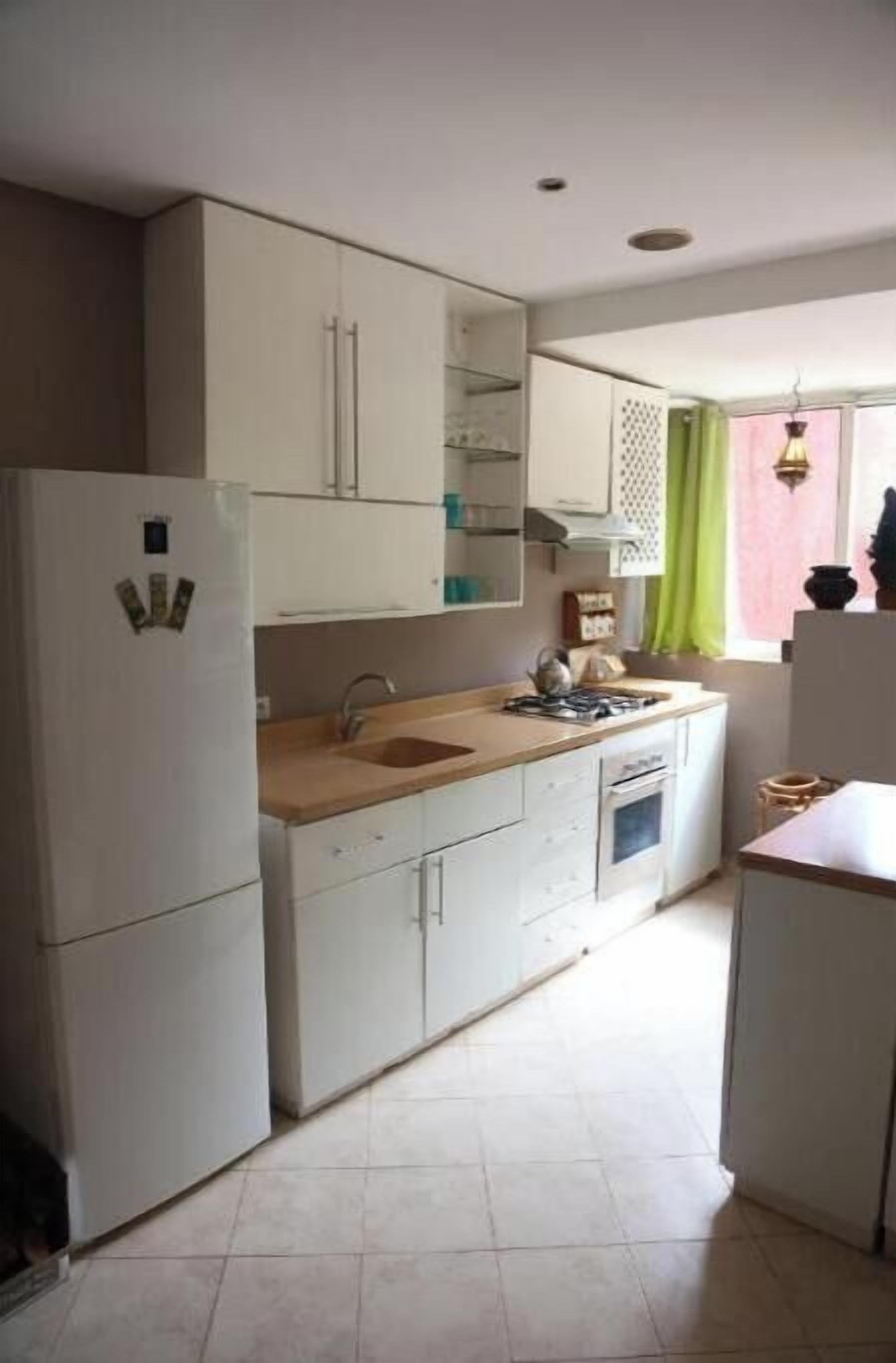 A compact kitchen with white cabinets, a sink, a stove, and a refrigerator.