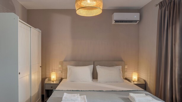 Hotellihuone, jossa on suuri sänky, kaksi yöpöytälamppua, ilmastointilaite ja vaatekaappi.