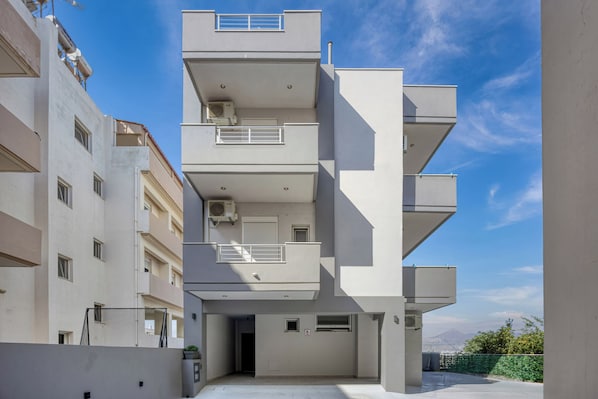 Un immeuble résidentiel à plusieurs étages, doté de balcons et de climatiseurs, avec un ciel dégagé.
