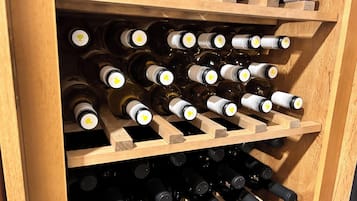 Una botellera de madera con varias botellas de vino, cada una con corcho y etiqueta visibles.