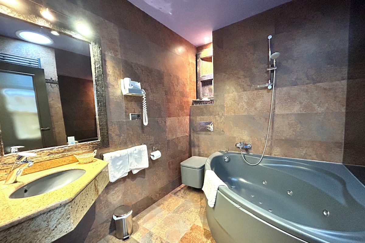 Une salle de bain moderne avec une grande baignoire, un lavabo et un miroir.