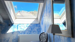 A room with a skylight, a round table, a zebra-patterned chair, a lamp, and a large mirror. - La Posada d'Àneu by RdA Hotels (Esterri D'Aneu)
