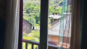 A view through a window with curtains, revealing a mountainous landscape with buildings. - La Posada d'Àneu by RdA Hotels (Esterri D'Aneu)