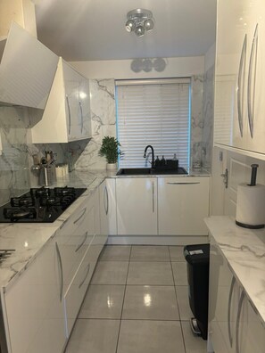 A modern kitchen with white cabinets, a black faucet, and a marble backsplash.